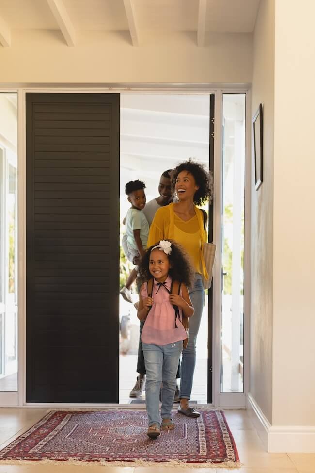 A family entering their home smiling